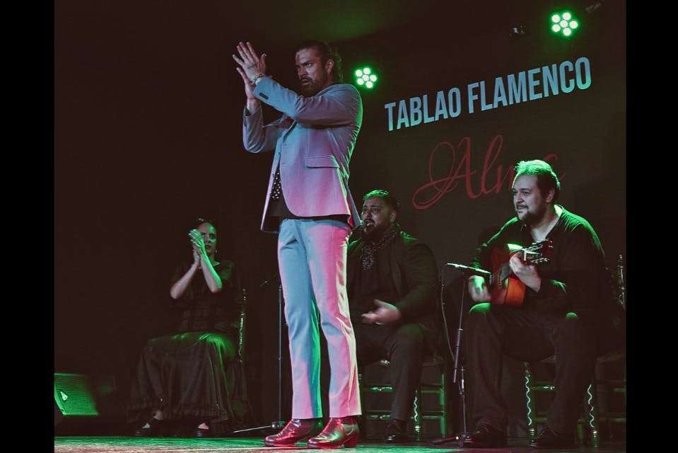 플라멩코 무용수가 무대에서 기타리스트와 가수와 함께 "Tablao Flamenco" 를 배경으로 공연합니다.