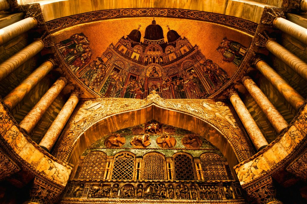 종교적 인물과 건축물을 묘사한 화려한 금빛 모자이크이며, 벽과 천장에 복잡한 패턴과 디자인이 있습니다.