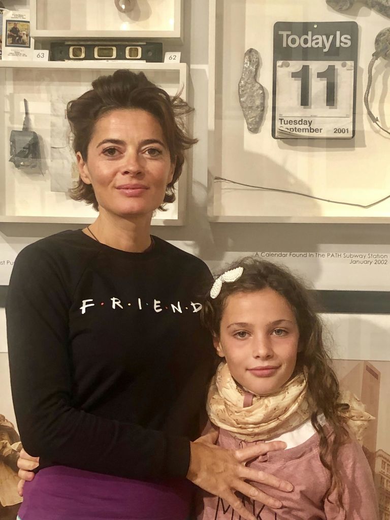 '친구' 라고 적힌 검은색 셔츠를 입은 여성과 스카프를 두른 어린이가 실내에 서 있습니다.