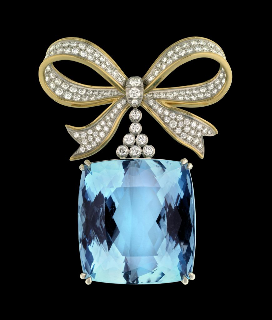 검은색 바탕에 다이아몬드로 둘러싸인 금색 활을 얹은 갈래 모양의 반짝이는 파란색 원석.