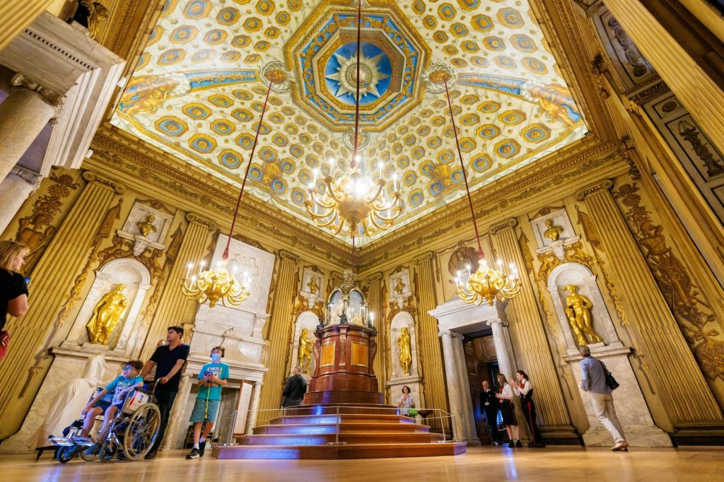 방문객들은 천장, 샹들리에, 동상, 정교한 목공예품이 있는 화려한 방을 탐험합니다.