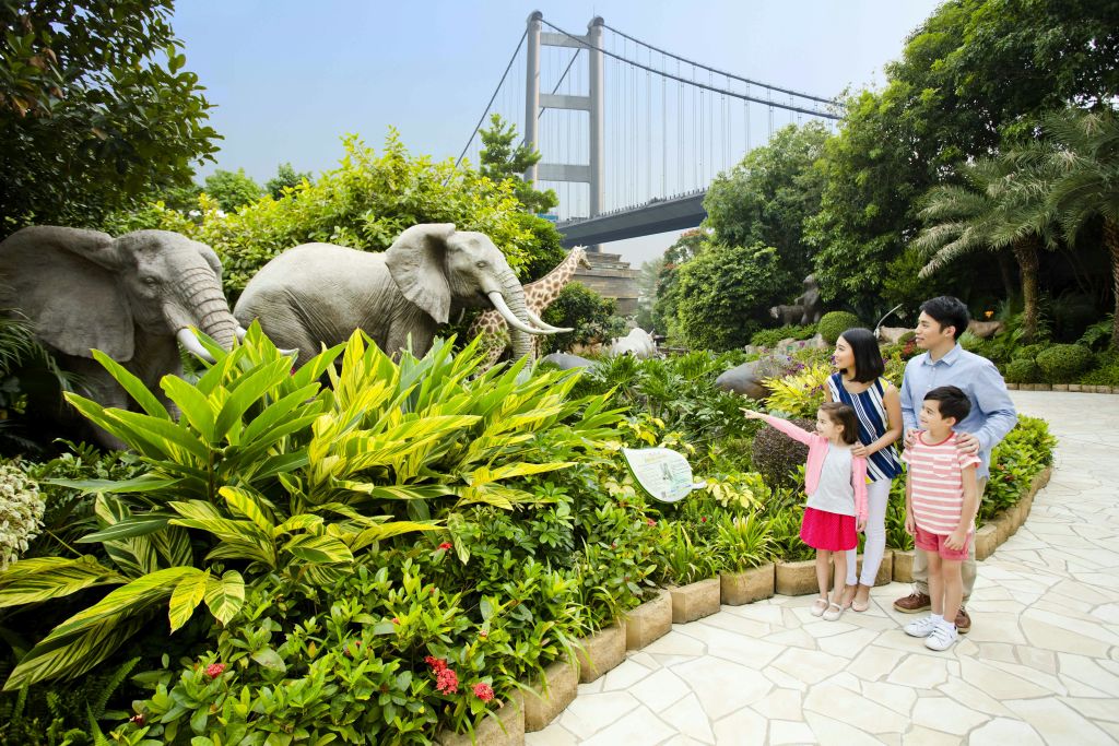 다리를 배경으로 울창한 공원에서 4명의 가족이 동물상을 감상하고 있습니다.