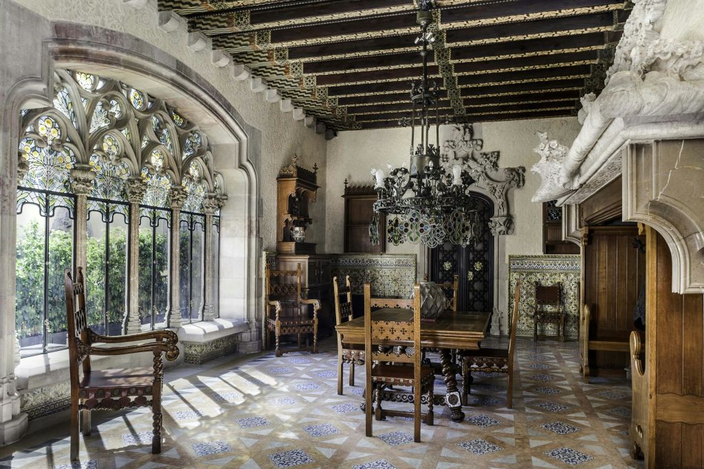 목재 가구, 스테인드글라스 창문, 샹들리에, 정교한 천장과 벽면 디자인으로 화려하게 꾸며진 식당.