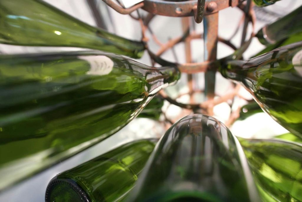 아래에서 본 금속 랙에 거꾸로 보관된 녹색 유리병.