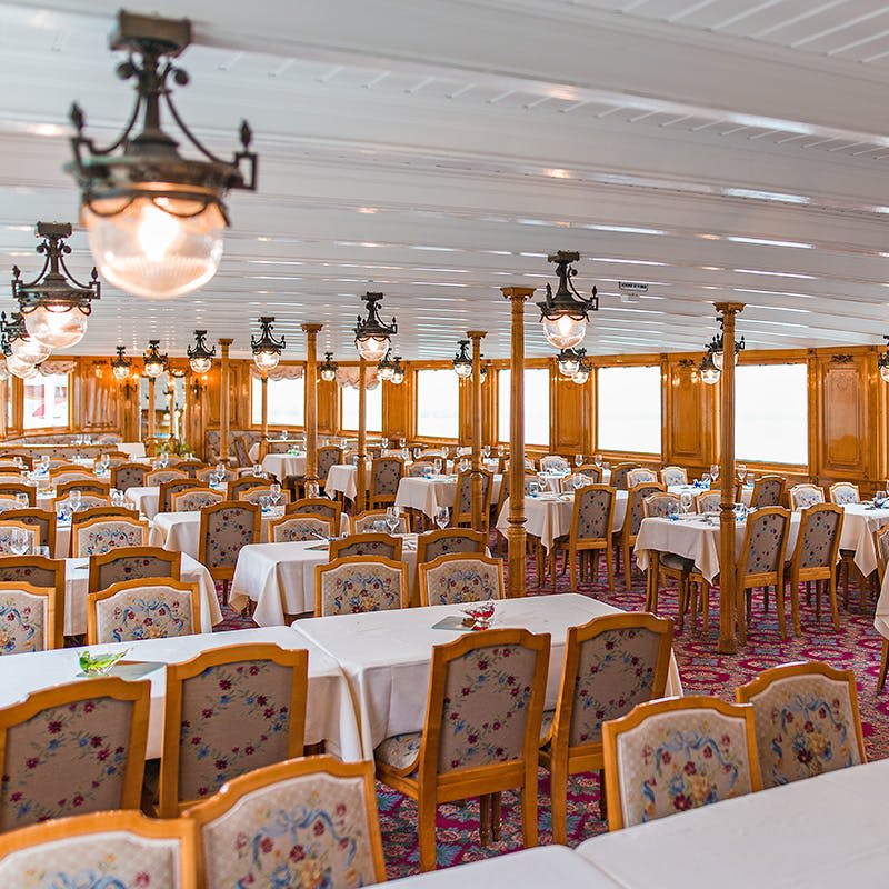 꽃무늬 의자, 흰색 식탁보, 빈티지 샹들리에가 있는 밝고 화려한 다이닝 룸입니다.