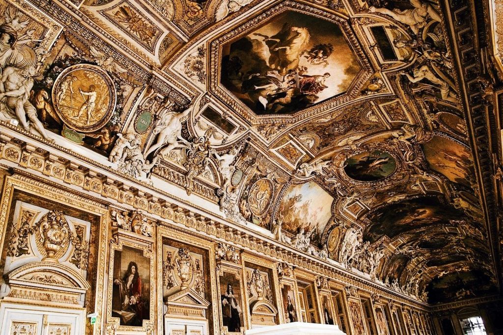 천장과 벽을 덮고 있는 섬세한 회화, 조각, 정교한 디자인이 돋보이는 화려하고 황금빛의 방입니다.