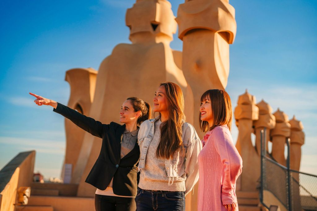 조각적인 요소가 돋보이는 옥상에 세 명의 여성이 서서 맑고 푸른 하늘 아래에서 전망을 즐기고 있습니다.