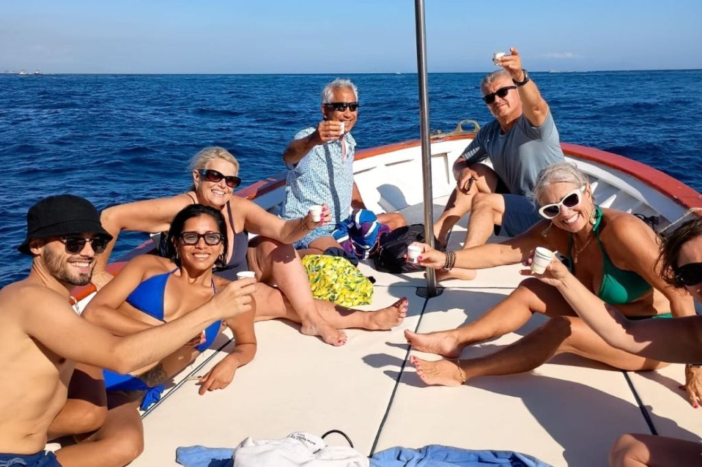 바다와 푸른 하늘을 배경으로 한 보트에서 음료를 즐기는 사람들.