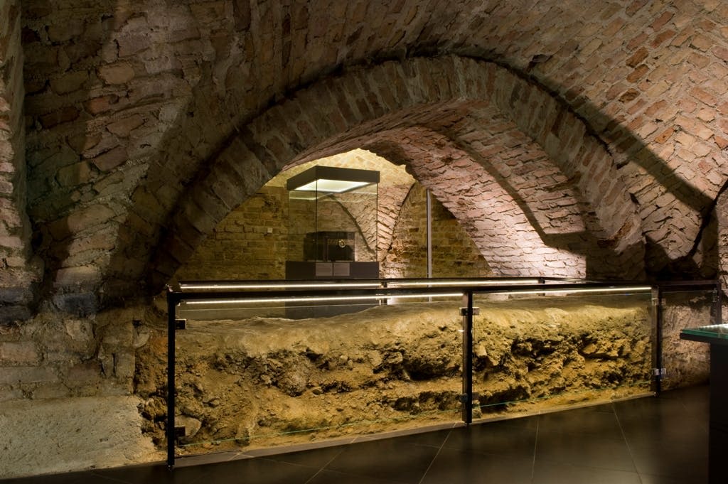 벽돌 아치길, 유리 진열장, 금속 난간이 있는 지하 공간.