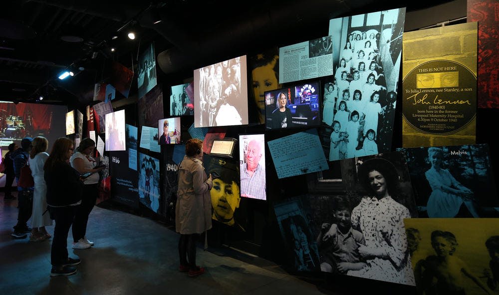 역사적인 이미지와 문서를 특징으로 하는 멀티미디어 벽면 디스플레이에서 다양한 사진과 동영상을 보는 사람.