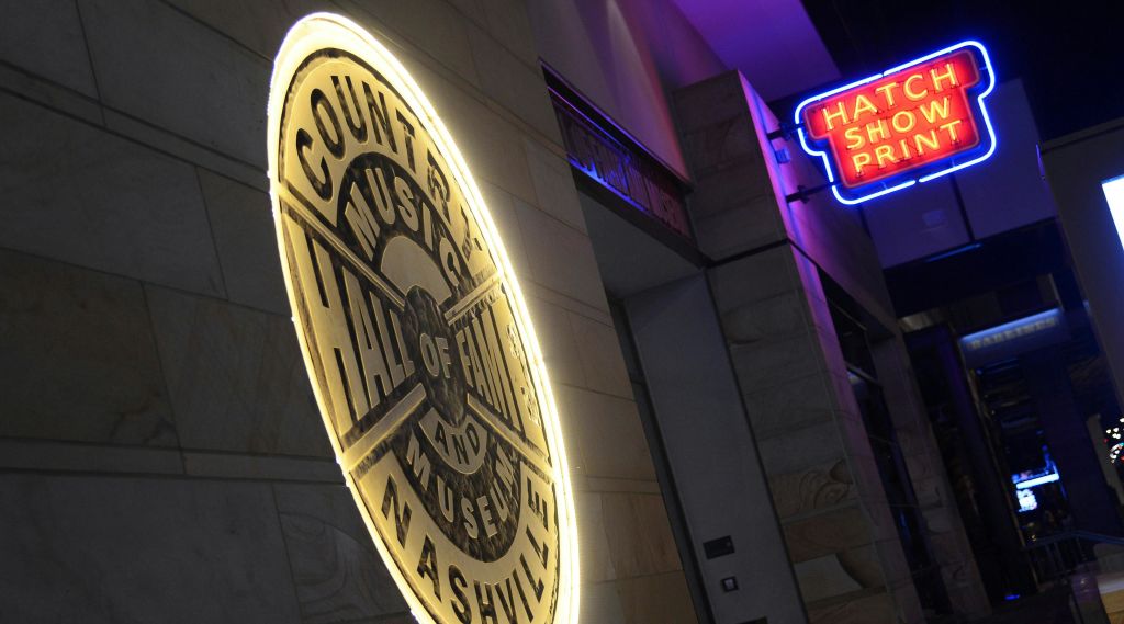 하드록 카페의 파란색과 빨간색 네온 사인 옆에 "컨트리 뮤직 명예의 전당 및 내슈빌 박물관" 이라는 조명 사인이 있습니다.