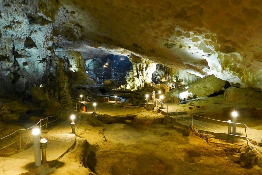 종유석, 석순, 난간이 있는 통로, 이 지역을 탐험하는 사람들이 있는 넓고 밝은 동굴입니다.