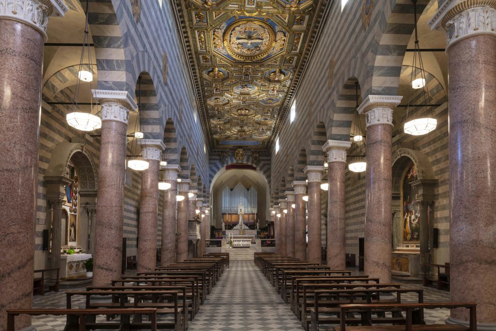 줄무늬 기둥이 있는 화려한 교회 내부, 금색 디테일이 있는 아치형 천장, 나무 페우, 맨 끝에 있는 제단.