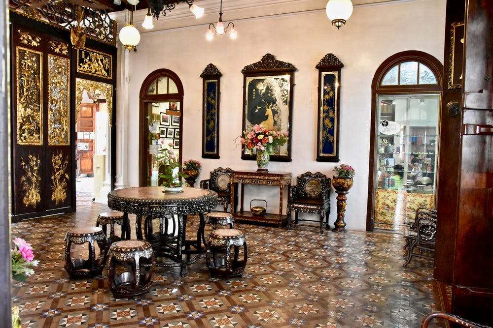 스툴이 있는 원형 테이블, 장식용 꽃병, 액자에 담긴 벽면 예술품, 아치형 출입구 등 앤티크 가구가 놓인 화려한 객실입니다.