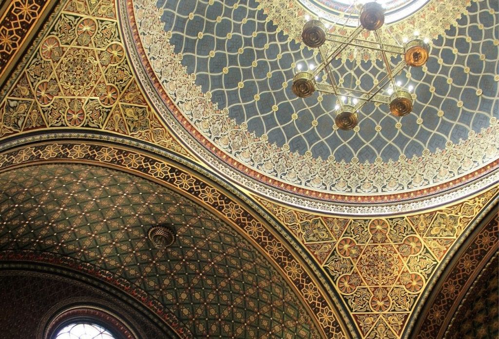 골드 액센트, 기하학적 디자인, 중앙에 샹들리에가 있는 정교한 패턴의 돔형 천장.