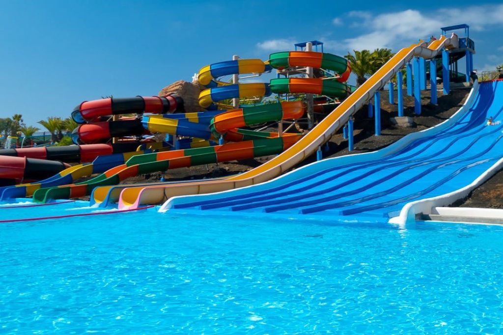 다채로운 물 미끄럼틀과 맑고 푸른 하늘 아래 수영장이 있습니다.