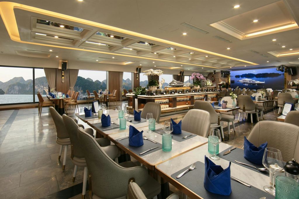 현대적인 인테리어의 우아한 레스토랑, 푸른 냅킨이 놓인 테이블, 유리 제품, 커다란 창문을 통해 나무의 전망을 감상할 수 있습니다.