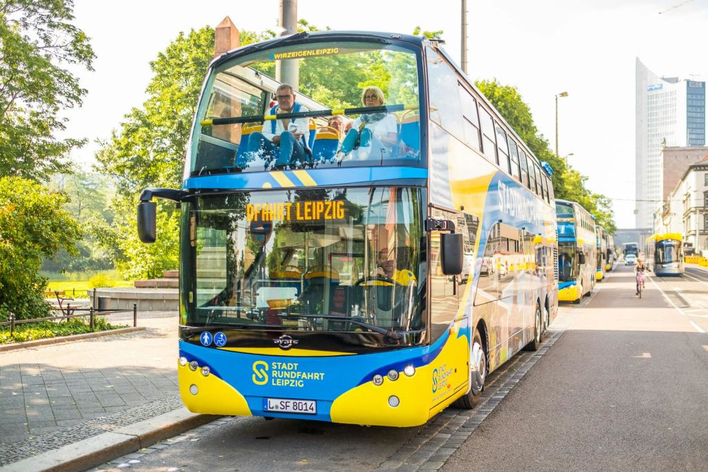 상부 갑판에 승객과 함께 라이프치히의 2층 투어 버스를 타고 화창한 날 연석에 주차합니다.