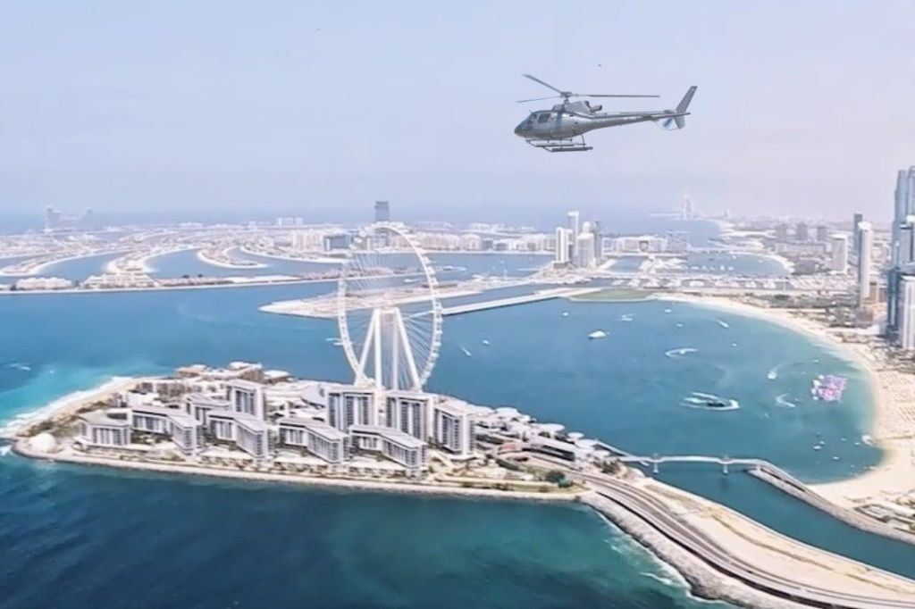 앵 두바이 (Ain Dubai) 와 블루 워터스 (Blue Waters) 위를 맴도는 검은 헬리콥터.