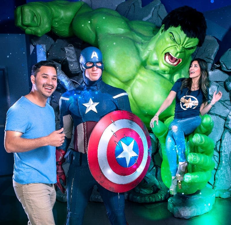 캡틴 아메리카와 함께 포즈를 취하는 두 사람과 헐크의 커다란 동상이 테마가 있고 코믹한 분위기를 풍깁니다.