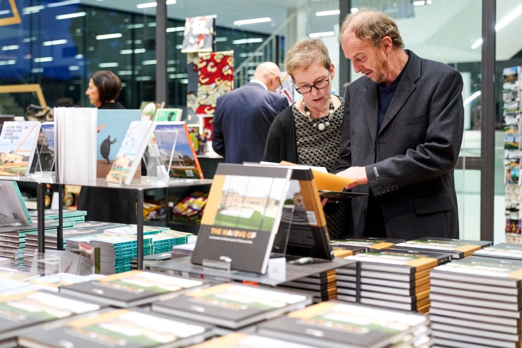 두 사람이 현대 서점의 테이블에 놓인 책을 둘러보고 있습니다. 배경에 다른 사람이 보입니다.