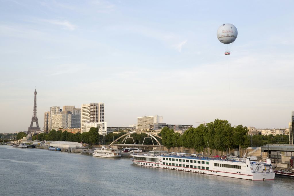 도킹한 보트, 다리, 도시 건물을 배경으로 한 강입니다. 열기구가 하늘에 떠 있습니다.