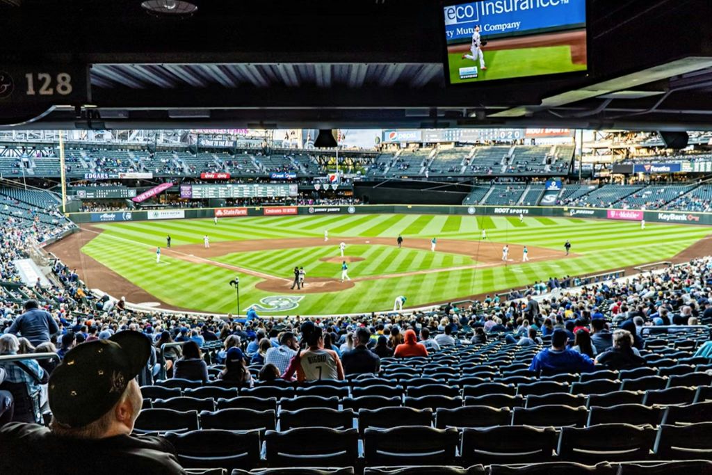 스탠드에서 바라본 경기장에서 진행 중인 야구 경기로, 경기장에 있는 선수들과 관객들이 지켜보고 있습니다.