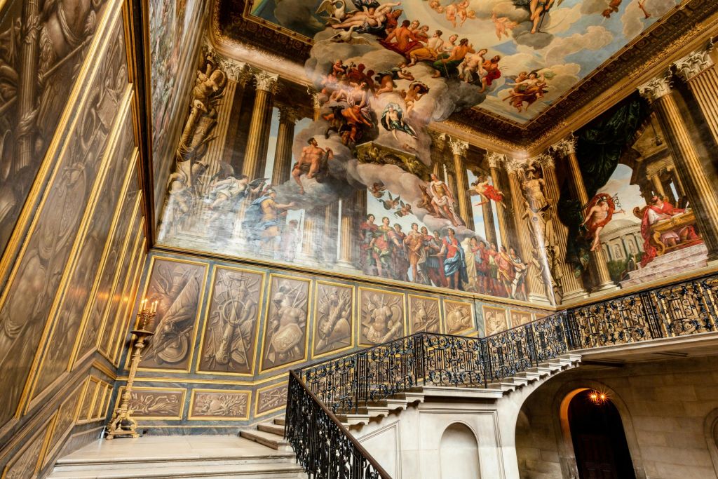 화려한 연철 난간이 있는 웅장한 계단, 정교하게 칠해진 벽과 천장 아래에는 역사적, 신화적 장면이 묘사되어 있습니다.