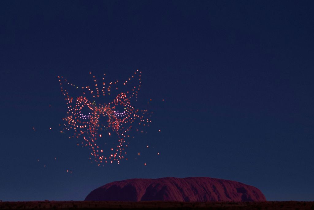 밤하늘에는 드론이 달빛이 비치는 울룰루를 닮은 커다란 암석 위에 빛나는 늑대 얼굴을 형상화하고 있습니다.