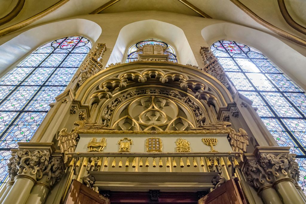 황금 조각과 상징이 있는 정교하고 디테일한 아치형 출입구로, 교회의 두 개의 스테인드글라스 창문으로 둘러싸여 있습니다.