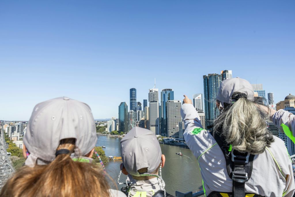 파란색 셔츠를 입은 한 무리의 사람들이 파란색과 흰색 보트를 배경으로 물 위 야외 계단을 오르고 있습니다.