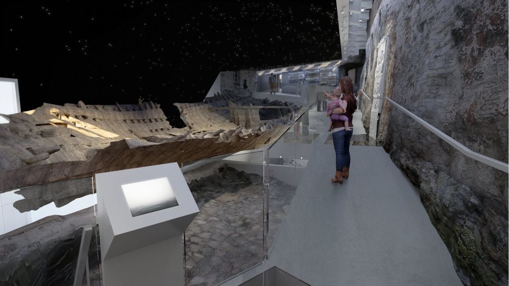 아기를 안은 여성이 별이 빛나는 하늘 천장 아래 현대 미술관 내부에서 고대 난파선 전시를 보고 있습니다.