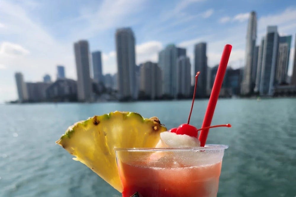 파인애플 슬라이스와 체리로 장식된 열대 칵테일의 클로즈업과 흐릿한 배경의 도시 스카이라인.