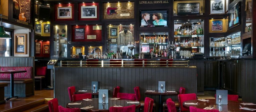 빨간색 의자가 놓인 바 내부, 식사를 위한 테이블, 잘 갖춰진 바, 벽에 액자에 담긴 기념품, 영화 장면을 보여주는 TV가 있습니다.