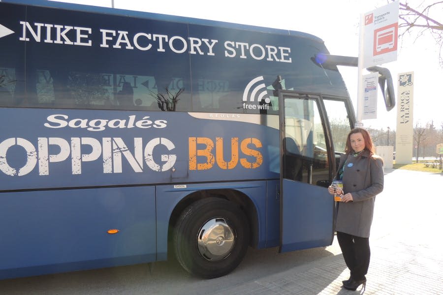 'HISTORY STORE' 와 'BIG BUS' 라고 적힌 파란색 투어 버스 옆에 한 여성이 브로셔를 들고 서 있습니다.