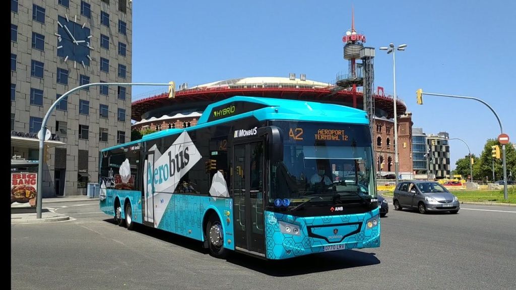 주변 건물이 있는 도심 지역의 공항 터미널로 향하는 '에어로버스' 라는 파란색 하이브리드 버스가 있습니다.