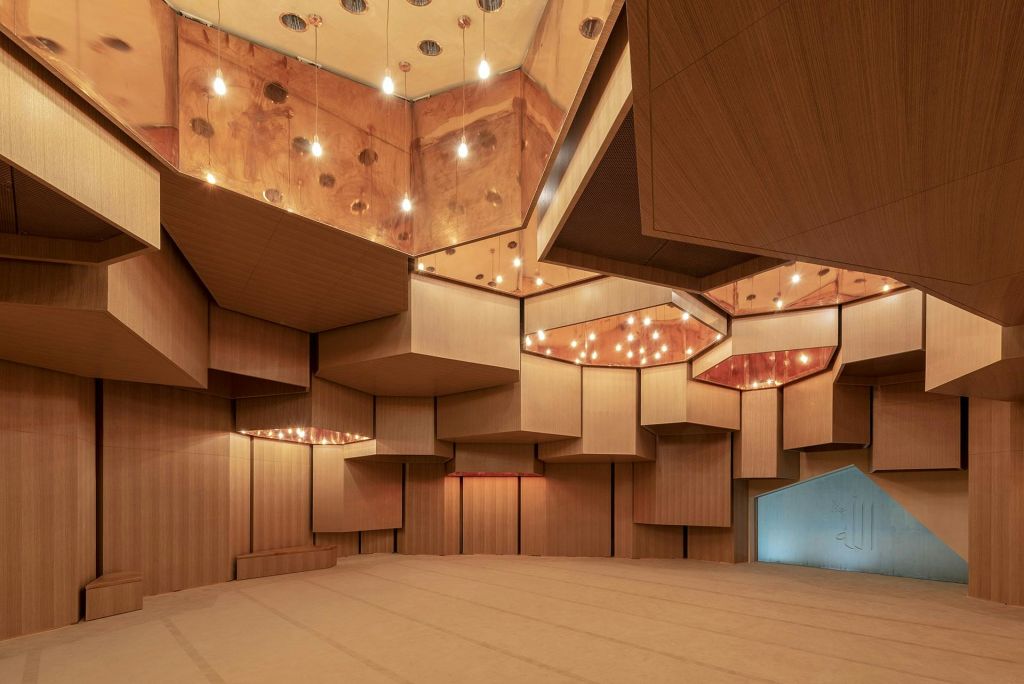 기하학적 목재 패널, 거울 천장, 여러 개의 매달린 조명이 있는 현대적인 객실입니다. 숙소가 비었습니다.