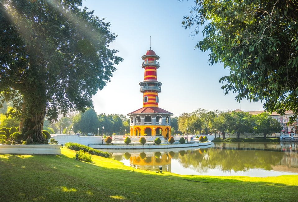 맑은 하늘 아래 나무와 녹음으로 둘러싸인 호수 근처에 빨간색과 노란색 줄무늬가 있는 화려한 탑.