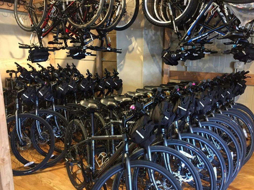 주차된 자전거와 선반에 매달린 추가 자전거를 포함한 자전거가 가득한 방.