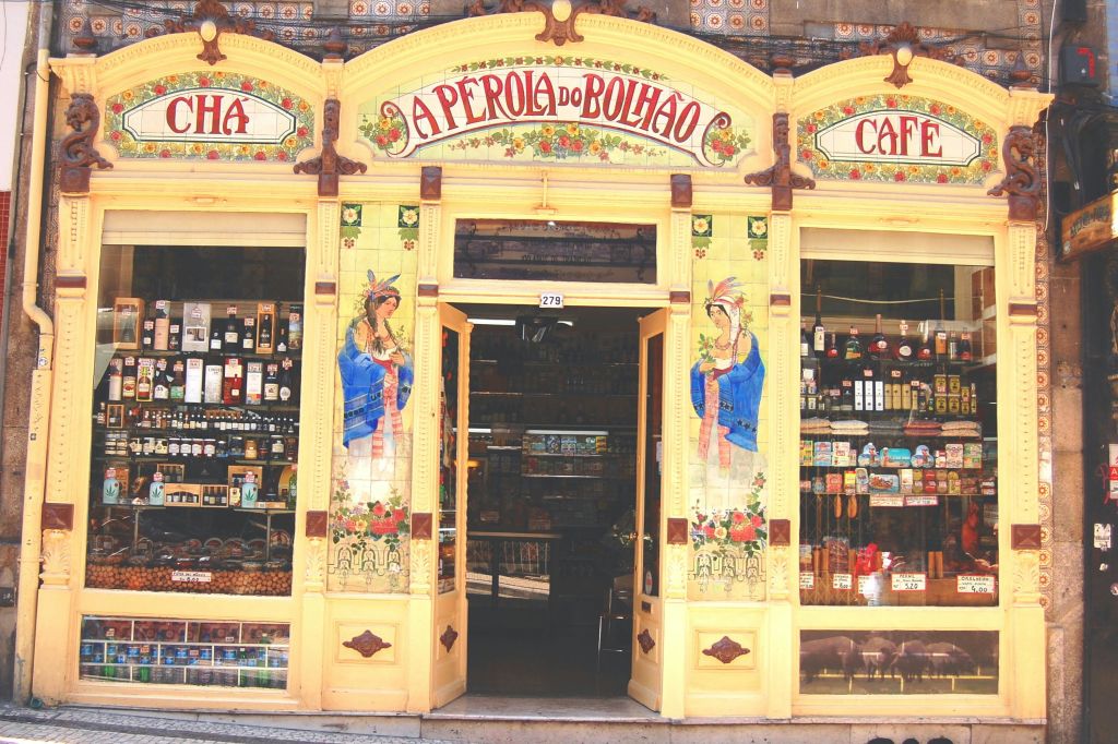 내부에 다양한 상품이 구비된 장식 벽화와 선반이 있는 "A Perola do Bolhao" 의 노란색 상점가.