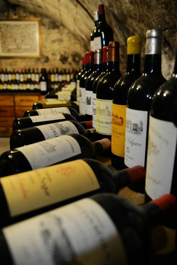 매장의 나무 선반에 와인병이 줄지어 놓여 있고, 선반을 배경으로 더 많은 병이 놓여 있습니다.