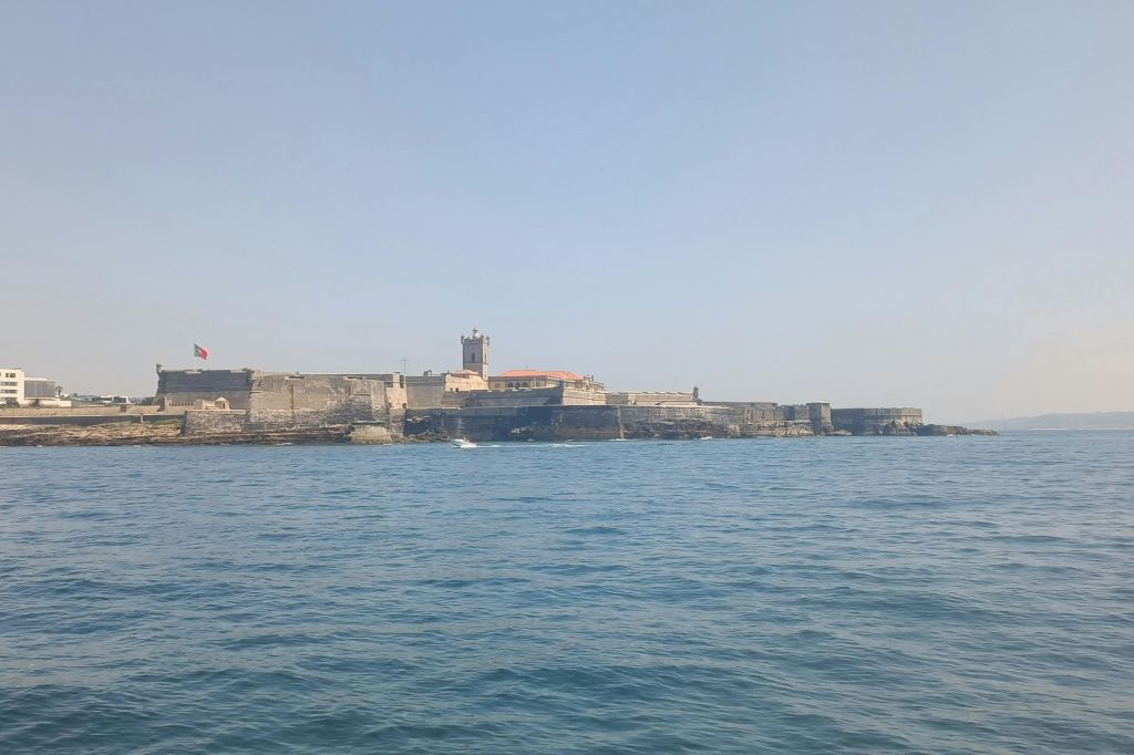 맑은 날 물가에서 보이는 돌담과 탑이 있는 해안 요새.