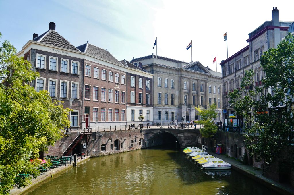 유서 깊은 건물과 아치형 다리가 늘어선 운하를 따라 자전거가 주차되어 있습니다.