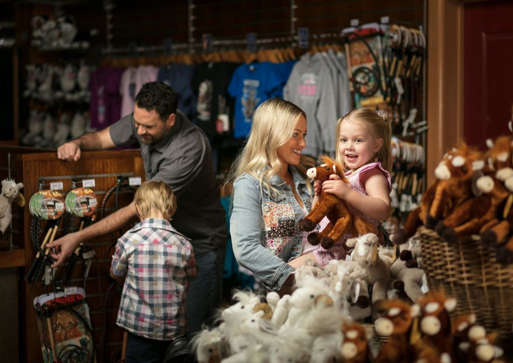 카운터에 있는 남성, 아이를 안고 있는 여성, 박제된 동물과 함께 상점에서 쇼핑하는 가족.