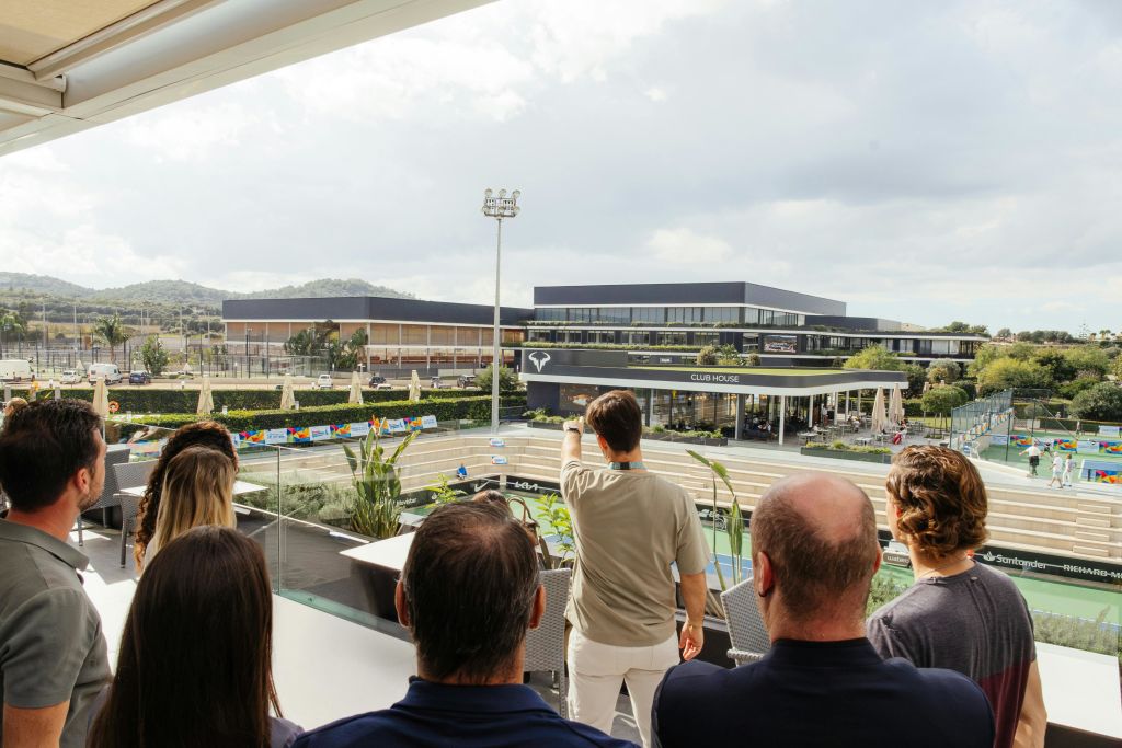 발코니에 앉아 흐린 하늘 아래 현대적인 클럽하우스와 스포츠 단지가 내려다보입니다.