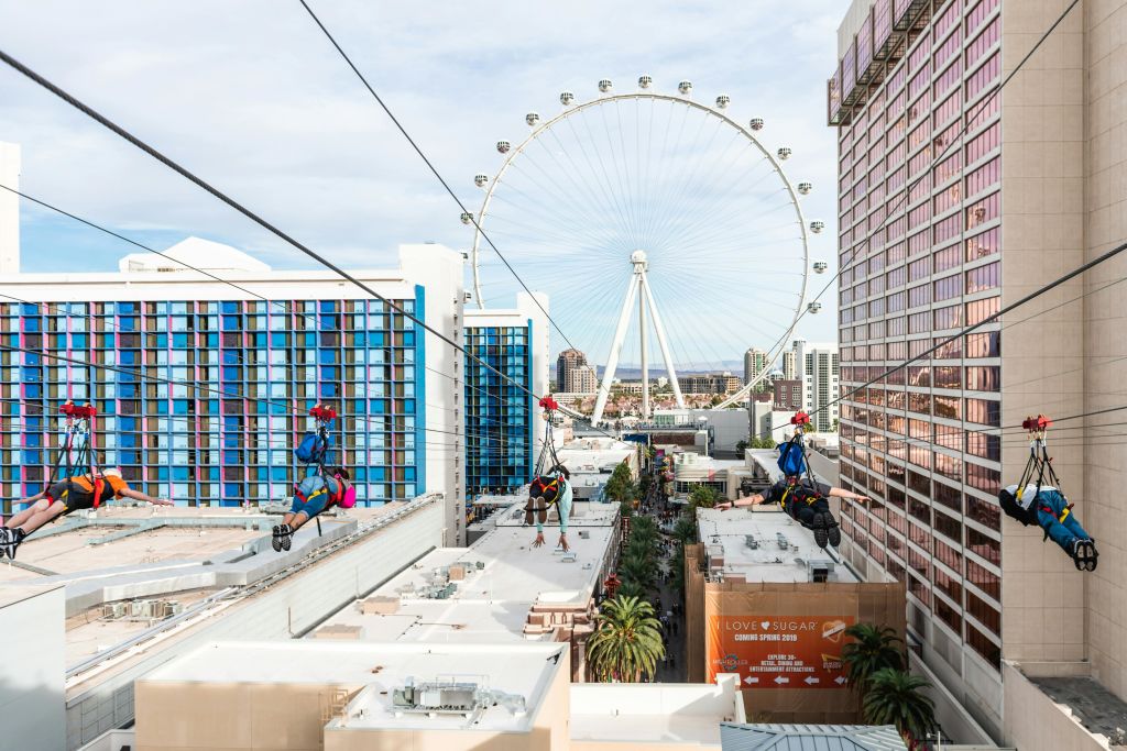 커다란 대관람차를 배경으로 건물이 즐비한 도시 거리 위를 세 사람이 집업하고 있습니다.