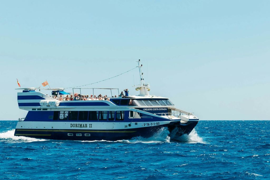 화창한 하늘 아래 맑고 푸른 물 위를 항해하는 도리마르 2세 (Dorimar II) 라는 이름의 여객선 상단 갑판에 사람들이 보입니다.