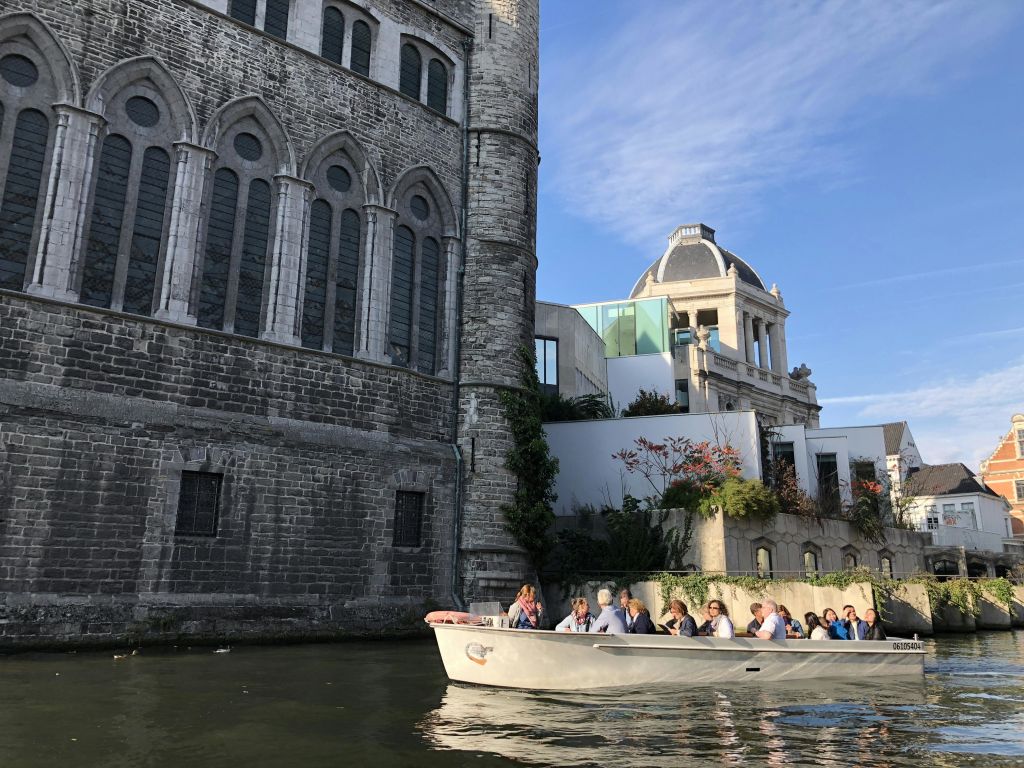 작은 투어 보트를 탄 사람들은 맑고 푸른 하늘 아래 운하를 따라 유서 깊은 석조 건물을 지나갑니다.