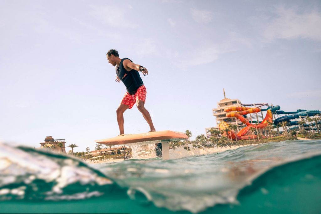 해변 근처의 수중 호일 서핑 보드를 배경으로 건물과 야자수가 조화를 이루고 있습니다.