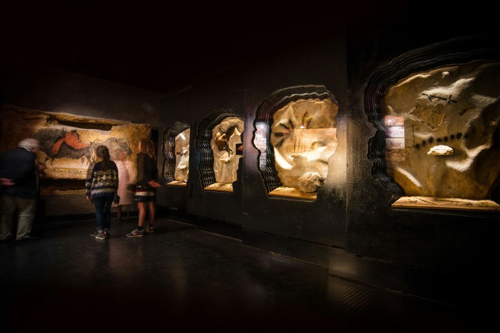 박물관과 같은 분위기에서 전시를 관람하는 두 사람의 암석층과 실루엣이 어둡게 빛나는 전시관입니다.